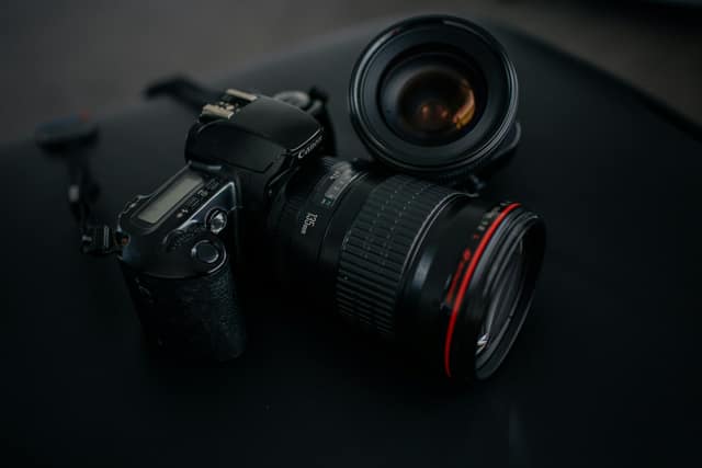 Camera body and a spare lens resting on a dark surface